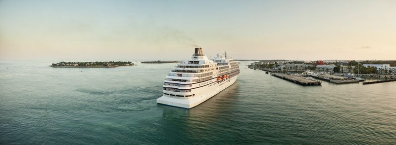 White cruise ship sailing out across calm water at dusk